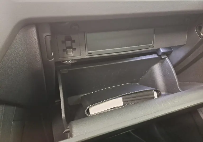 Gant de boîte à gants ouvert montrant un carnet noir avec surpiqûres blanches dans un Volkswagen Tiguan 2023.