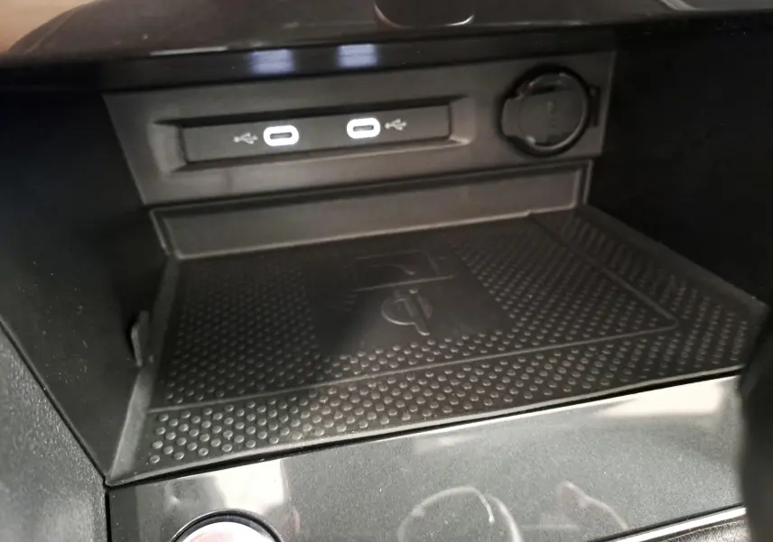 Gros plan sur la console centrale noire du Volkswagen Tiguan 2023, montrant les ports USB-C et le chargeur sans fil.