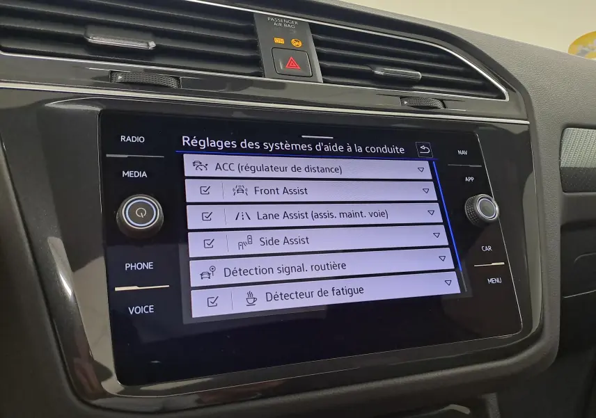 Écran tactile central du Volkswagen Tiguan 2023 affichant les réglages des aides à la conduite, intérieur noir.