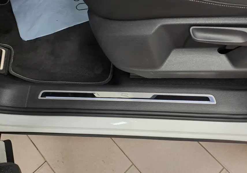 Seuil de porte côté gauche du Volkswagen Tiguan blanc pur, avec logo R-Line visible sur la garniture.
