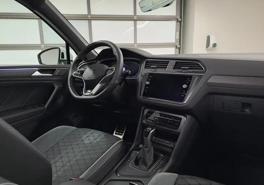 Intérieur avant du Volkswagen Tiguan 2023, vue côté conducteur, tableau de bord noir avec volant sport multifonction et écran tactile.