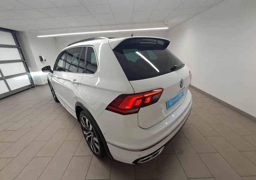 Volkswagen Tiguan blanc pur en 3/4 arrière droit, avec jantes alliage 20'' et toit ouvrant panoramique visible.
