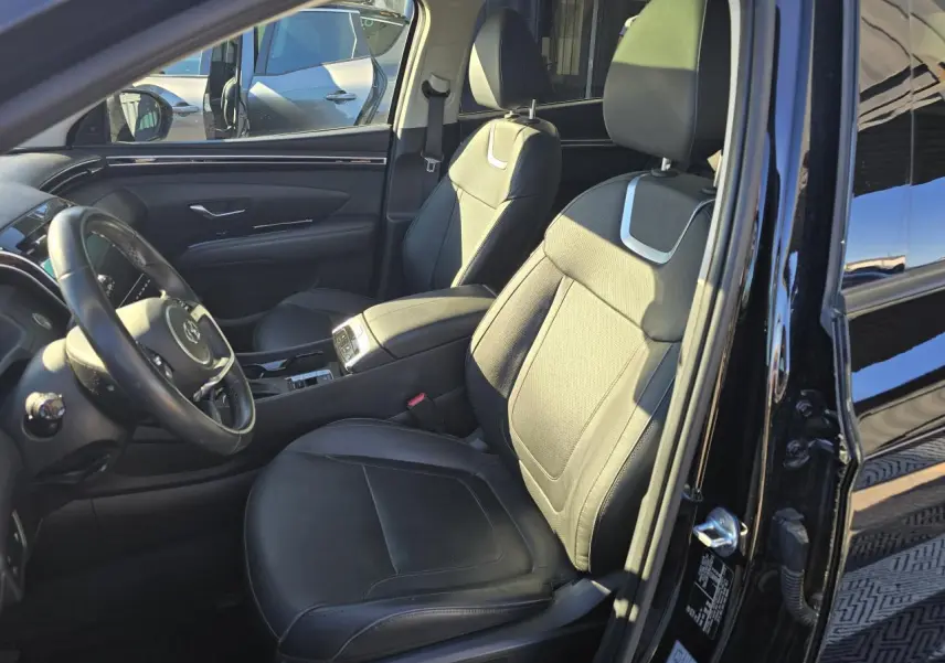 Vue intérieure côté conducteur du Hyundai Tucson noir Phantom Metal, mettant en valeur les sièges en cuir et la console centrale.
