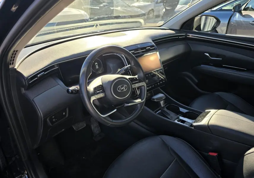 Vue intérieure côté conducteur du Hyundai Tucson noir Phantom Metal 2021, avec tableau de bord moderne et écran tactile central.