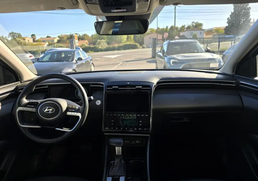 Vue intérieure avant du Hyundai Tucson noir Phantom Metal 2021, mettant en valeur le tableau de bord et le volant multifonction.