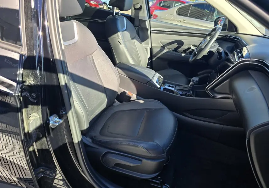 Vue intérieure côté gauche du Hyundai Tucson noir Phantom Metal 2021, mettant en valeur les sièges cuir noirs et la console centrale.