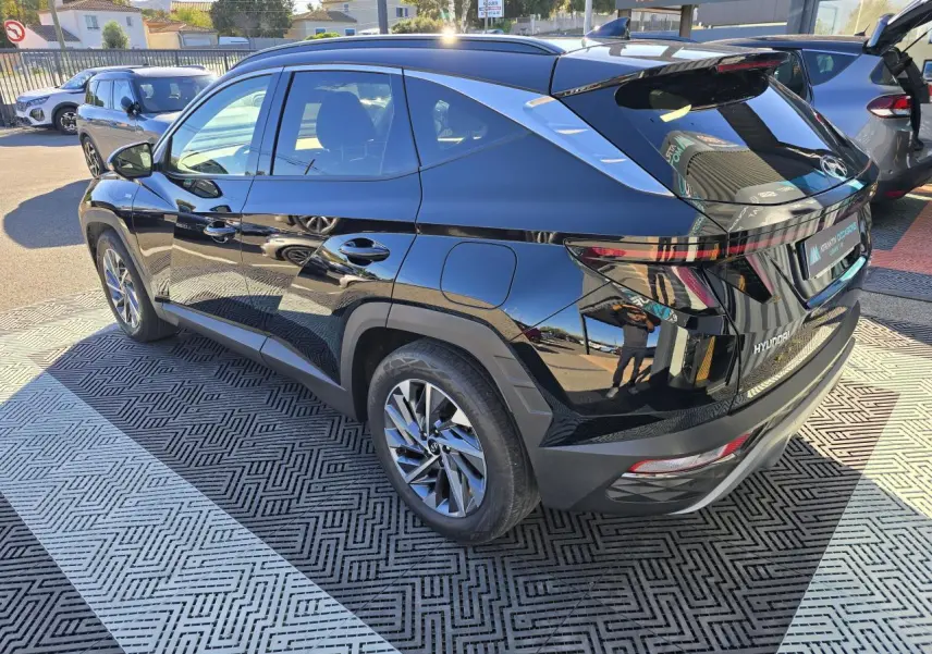 Vue 3/4 arrière droite d’un Hyundai Tucson noir Phantom Metal avec jantes alliage et toit panoramique visible.