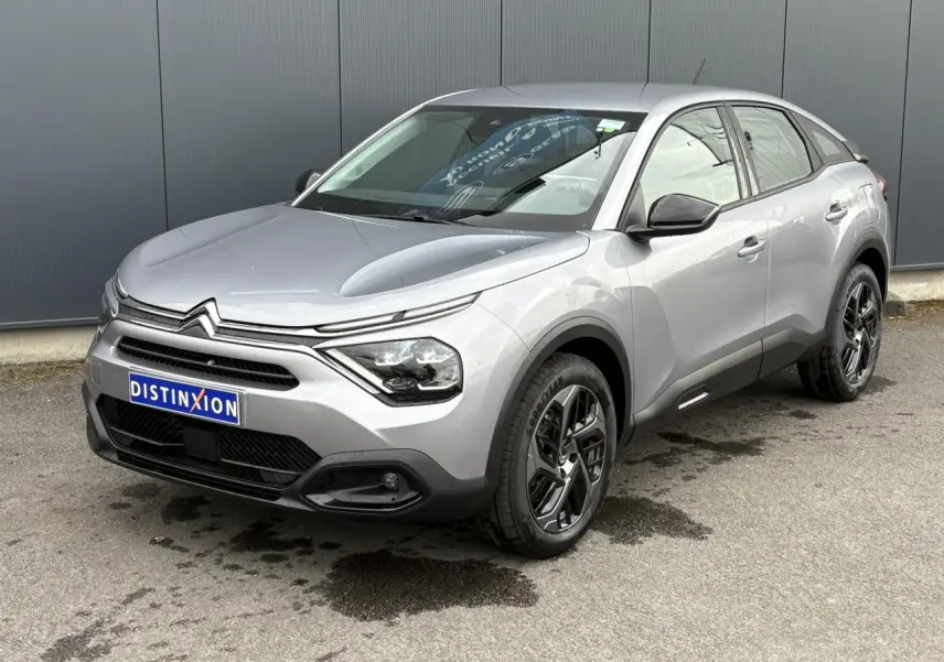 Citroën C4 gris acier vue 3/4 avant droit, avec jantes alliage noires et phares LED distinctifs.