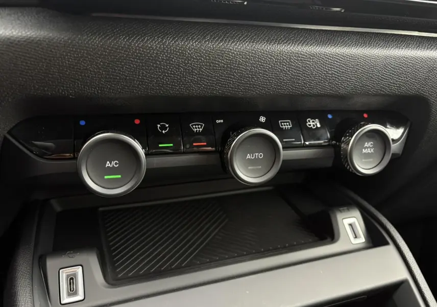 Gros plan sur la console centrale de la Citroën C4 2024, montrant les commandes de climatisation automatique et une prise USB.