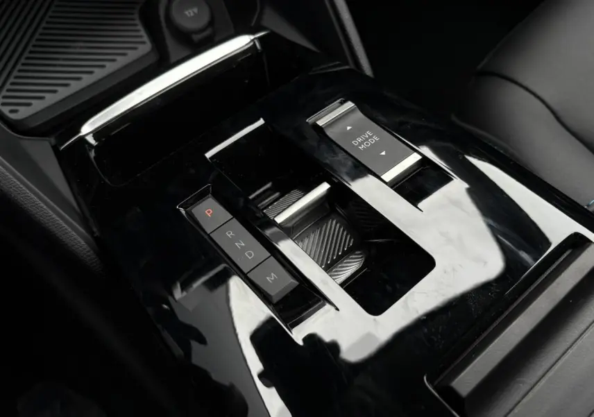 Gros plan sur la console centrale noire brillante de la Citroën C4 1.5 BlueHDi 130 avec sélecteur de boîte auto et commande Drive Mode.