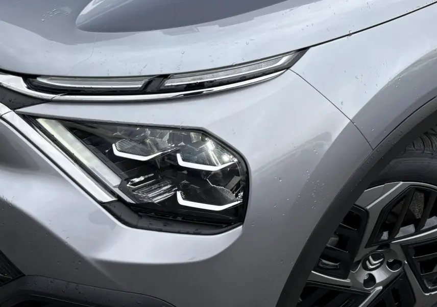 Gros plan sur le phare avant gauche LED et la jante alliage noire du Citroën C4 gris acier 2024.