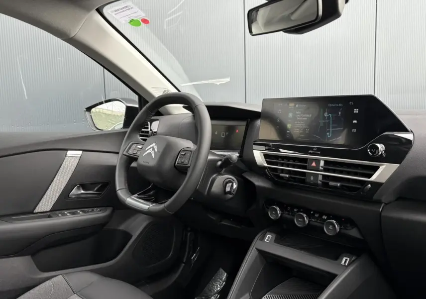 Intérieur de la Citroën C4 2024 vu côté conducteur, tableau de bord moderne avec écran tactile et volant cuir noir.