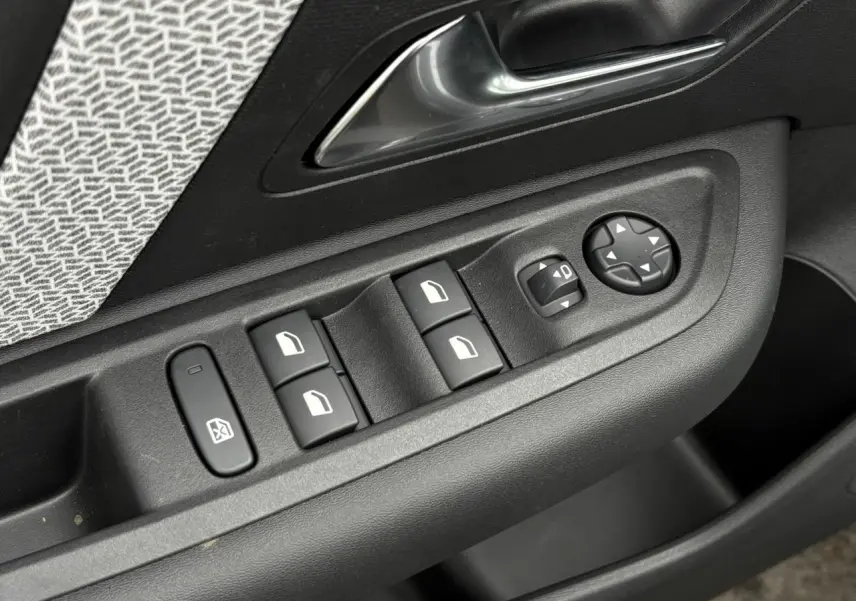 Gros plan sur les commandes de lève-vitres et réglages des rétroviseurs côté conducteur d’une Citroën C4 gris acier.