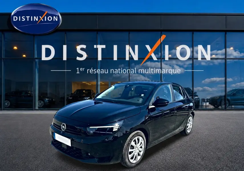 Opel Corsa noire vue en 3/4 avant droit, avec jantes argentées, devant une vitrine Distinxion.