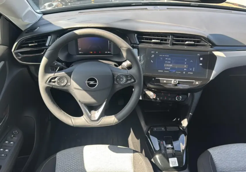 Vue intérieure avant de l’Opel Corsa noire 2025, avec volant multifonction, écran tactile et sièges tissu bicolore.