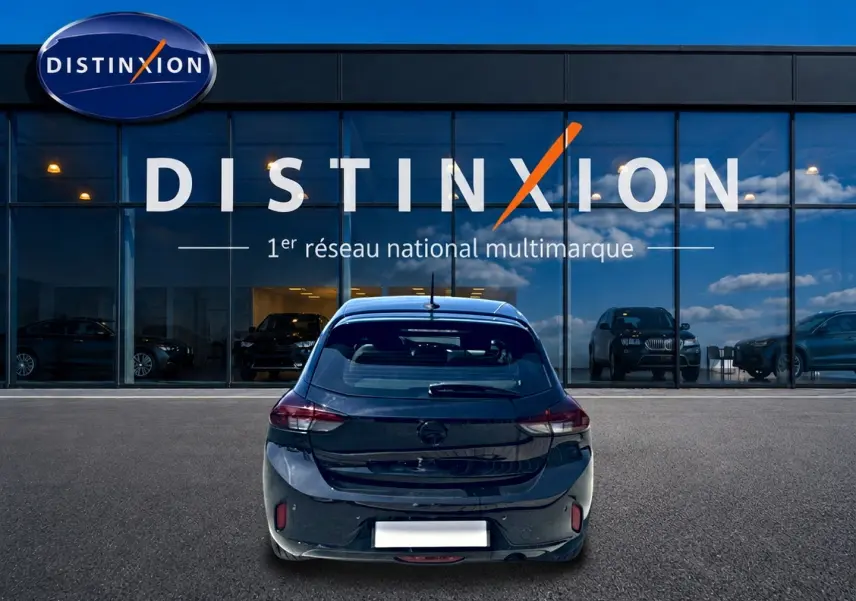 Vue arrière d'une Opel Corsa noire 2025 garée devant une vitrine avec logo Distinxion en arrière-plan.