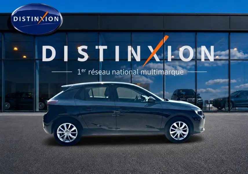 Profil côté gauche d'une Opel Corsa noire 2025 garée devant une vitrine avec logo Distinxion.