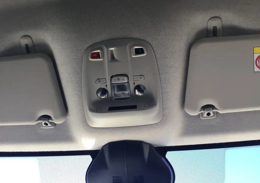 Plafonnier central avec commandes d’éclairage et pare-soleil gris clair dans un Peugeot Expert Fourgon blanc 2024 vue intérieure avant.
