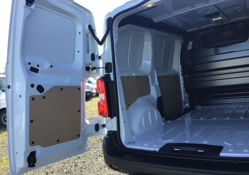 Vue arrière ouverte du Peugeot Expert Fourgon blanc 2024 montrant l'espace de chargement vide avec panneaux de protection intérieurs.
