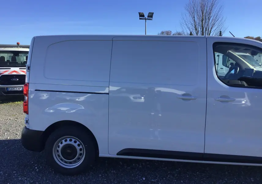 Profil côté gauche du fourgon blanc Peugeot Expert 2024, mettant en valeur sa carrosserie lisse et ses roues acier simples.