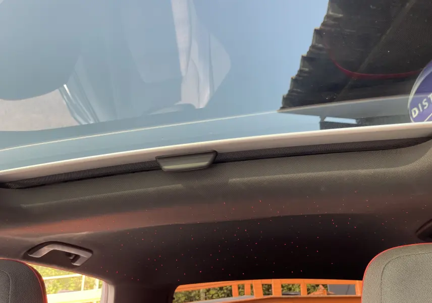 Toit panoramique ouvert montrant l'intérieur noir avec points lumineux rouges d'une Volkswagen Golf VIII GTI gris 2021