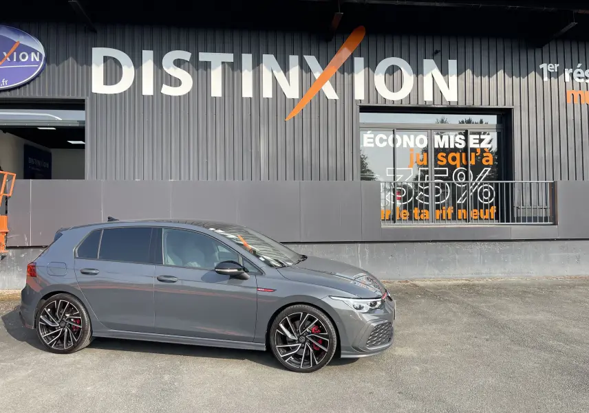 Volkswagen Golf VIII GTI gris vue de profil côté gauche, avec jantes noires et étriers de frein rouges visibles.