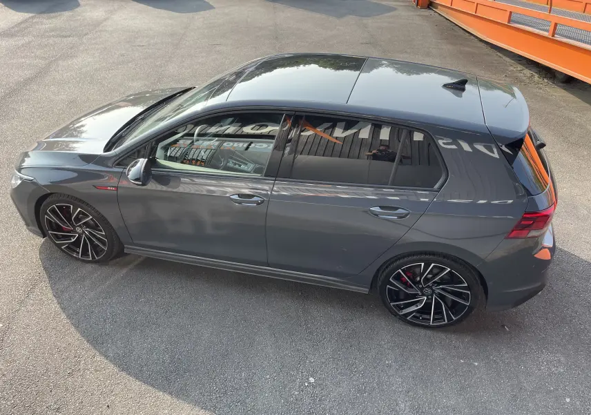 Vue de dessus côté gauche d'une Volkswagen Golf VIII GTI gris métallisé avec jantes noires et étriers rouges.