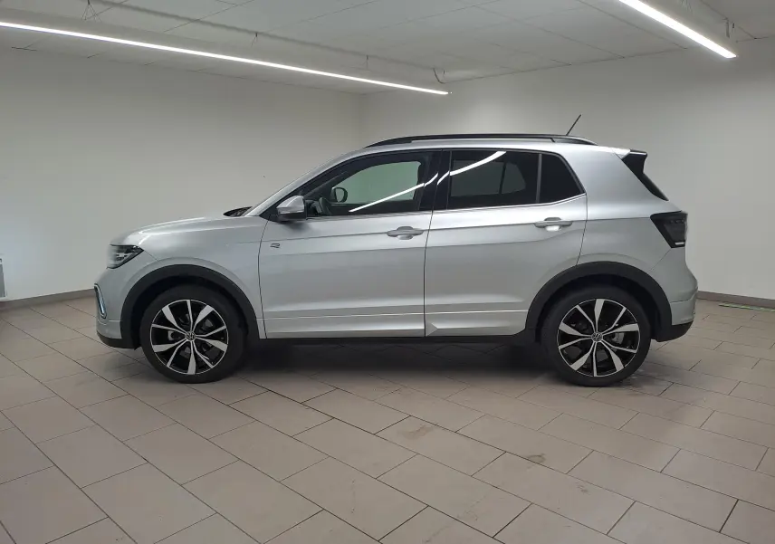 Profil côté gauche d'un Volkswagen T-Cross 2025 argent métallisé avec jantes alliage 18 pouces et finition R-Line.