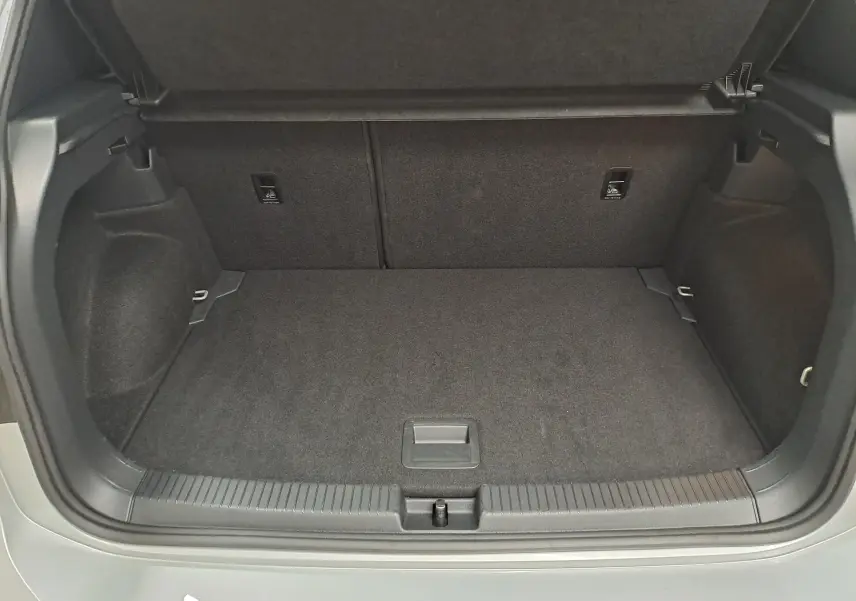 Coffre ouvert vu de l'arrière d'un Volkswagen T-Cross 2025 gris Reflet d'argent, espace de chargement vide et propre.