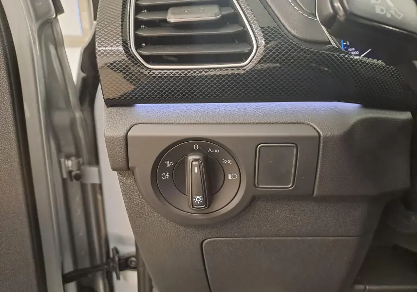 Gros plan sur le bouton de commande des phares côté gauche du tableau de bord d'un Volkswagen T-Cross argenté 2025.