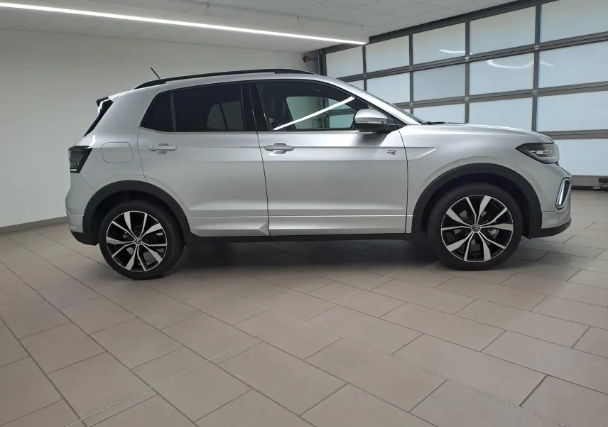 Profil droit d'un Volkswagen T-Cross 2025 R-Line Edition argent métallisé avec jantes alliage 18 pouces dans un showroom.