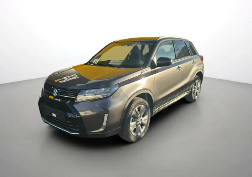 Suzuki Vitara 2025 gris titan en 3/4 avant droit, avec calandre noire et jantes alliage visibles.