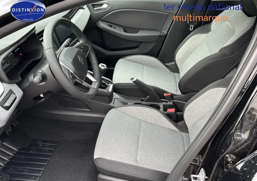 Intérieur avant droit de la Renault Clio V noire 2025 avec sièges bicolores gris et noir et volant multifonction.