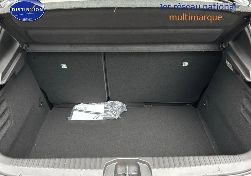 Vue intérieure du coffre ouvert de la Renault Clio V noire, montrant l'espace de rangement et la banquette arrière rabattable.