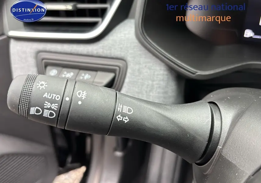 Gros plan sur la commande des feux et clignotants côté gauche du volant d’une Renault Clio V noire.