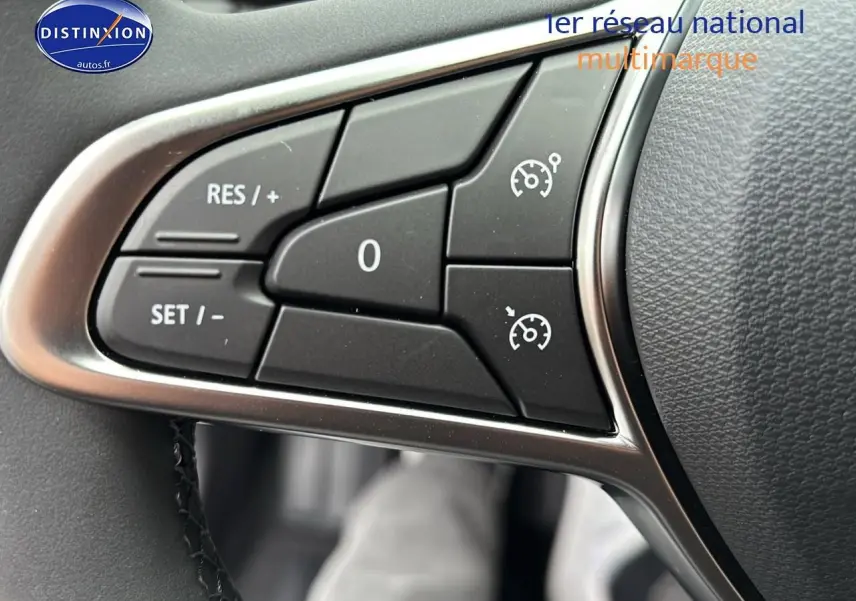 Gros plan sur les commandes du régulateur de vitesse au volant d'une Renault Clio V noire, intérieur moderne.