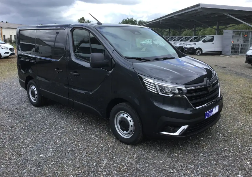 Renault Trafic Fourgon gris comète vu en 3/4 avant droit, avec calandre noire et phares LED distinctifs.