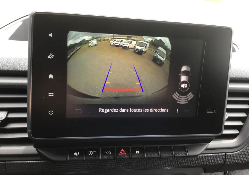 Écran tactile intérieur montrant la caméra de recul du Renault Trafic Fourgon gris comète, avec lignes de guidage colorées.