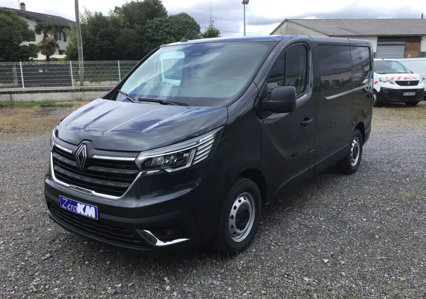 Vue 3/4 avant droit du Renault Trafic Fourgon gris comète avec calandre chromée et phares LED visibles.