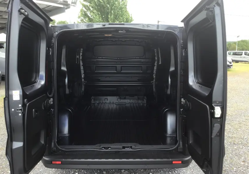 Vue arrière ouverte du Renault Trafic Fourgon gris comète 2025, montrant l'espace de chargement vide et les portes battantes ouvertes.