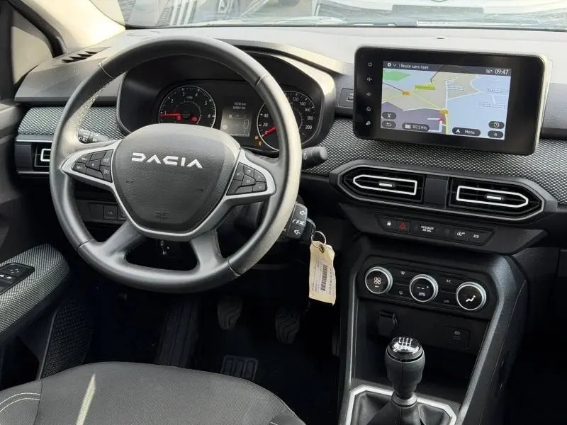 Vue intérieure du tableau de bord du Dacia Jogger 2025 avec volant multifonction, écran tactile et levier de vitesses manuel.