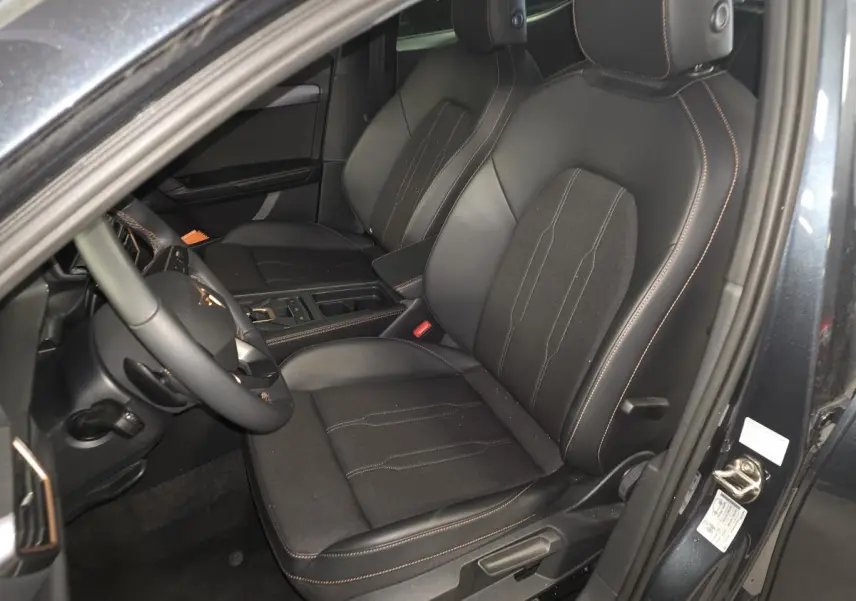 Vue intérieure côté conducteur de la CUPRA Leon gris, sièges sports bimatière noir avec surpiqûres cuivrées.