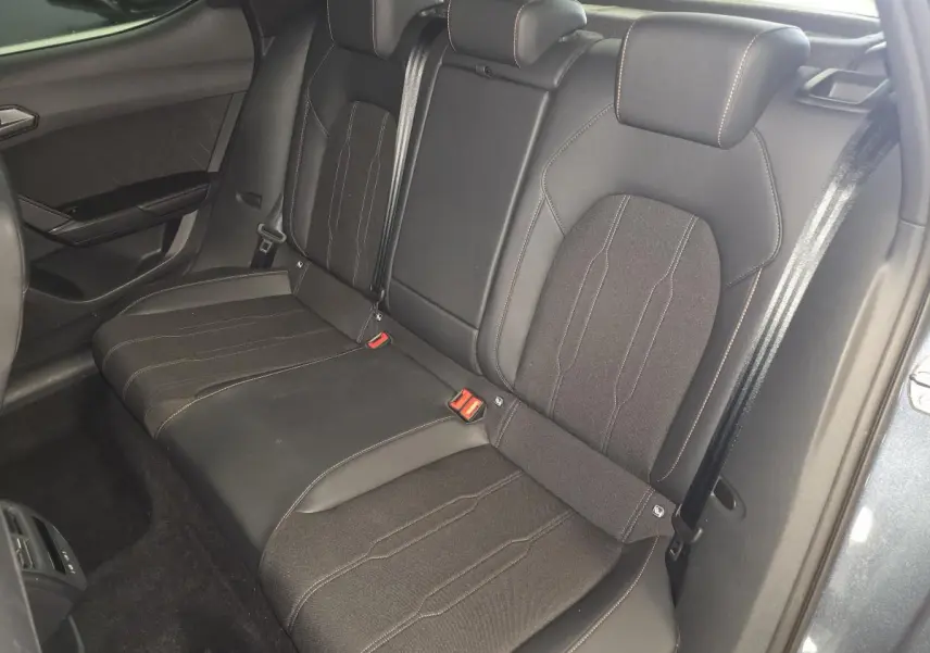 Vue intérieure arrière montrant la banquette bimatière noire du CUPRA Leon 2025 avec surpiqûres cuivrées.