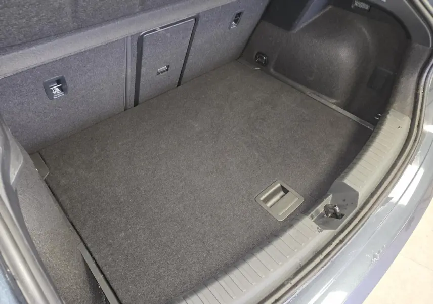 Vue plongeante sur le coffre spacieux et propre d'une CUPRA Leon gris, avec revêtement intérieur sombre et finitions nettes.