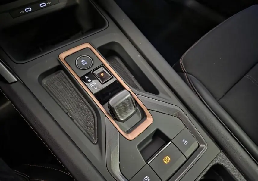 Gros plan sur la console centrale noire avec levier de vitesse et surpiqûres cuivrées dans une CUPRA Leon gris 2025.