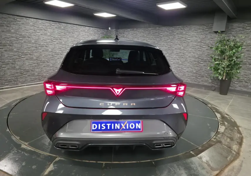 Vue arrière d'une CUPRA Leon gris magnétique avec feux arrière en bandeau lumineux Tri-LED et double sortie d'échappement noire.