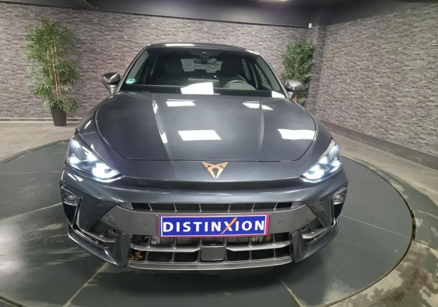 Vue avant d'une CUPRA Leon gris magnétique avec phares Tri-LED allumés et logo CUPRA cuivré sur le capot.