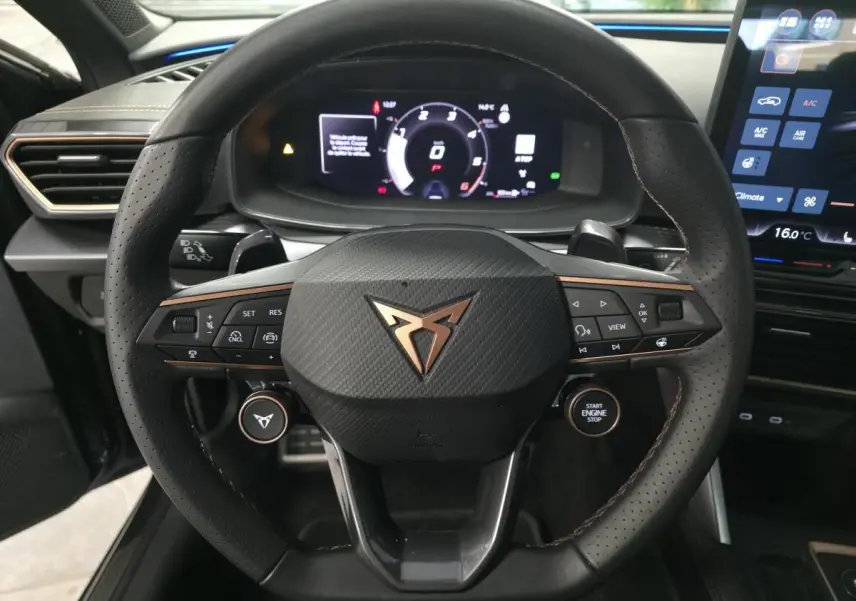 Vue rapprochée du volant cuir perforé noir avec logo CUPRA cuivré et tableau de bord digital du Leon 2.0 TDI gris 2025.