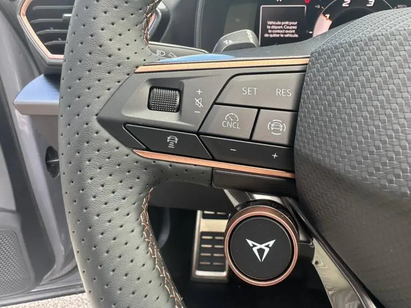 Gros plan sur le volant perforé gris avec commandes intégrées et logo CUPRA cuivré du Formentor 2.0 TDI 2025.