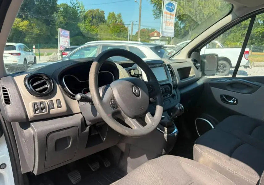 Vue intérieure côté conducteur du Renault Trafic Fourgon blanc de 2018, avec tableau de bord et volant visibles.